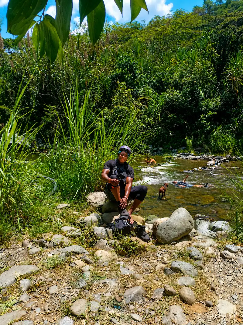 Ciclista descansando sobre las rocas del río Pance mientras otras personas se bañan, Cali