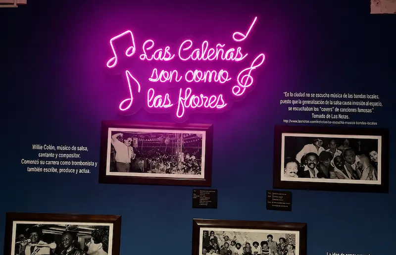 Letrero de neón "Las Caleñas son como las flores" y retratos de músicos de salsa