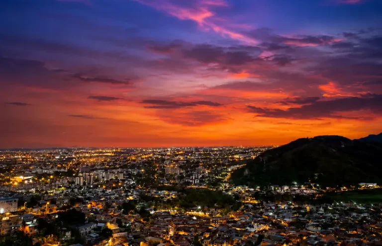 Atardecer anaranjado sobre Cali con la ciudad iluminada, visto desde los cerros de la Comuna 20